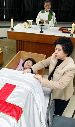 16일 서울 명동성당 옆 가톨릭회관 3층 대강당에서 김보록 신부가 ‘자신을 위한 장례미사와 고별식’을 집전하는 모습. 참가자들이 관 속에 들어가 죽음을 체험하고 있다. 